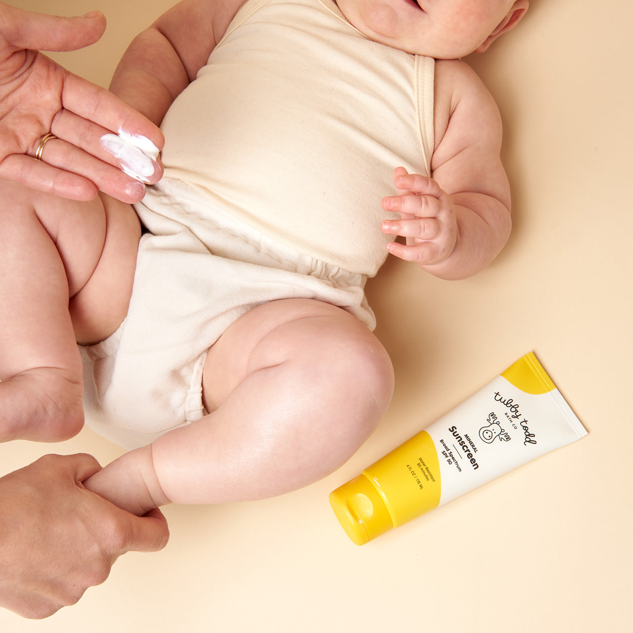 Mama applying Mineral Sunscreen to baby's thigh